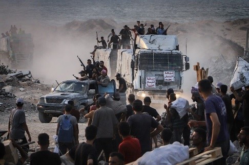 Gewapende Palestijnen zitten op vrachtwagens met humanitaire hulp bij de grensovergang Zikim tussen Israël en Beit Lahia in het noorden van de Gazastrook, 18 augustus 2025. Foto door Khalil Kahlout/Flash90.